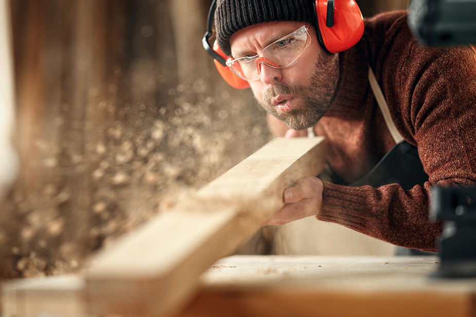 A Superior Skilled Trades commercial construction staff member wearing PPE working on a piece of wood