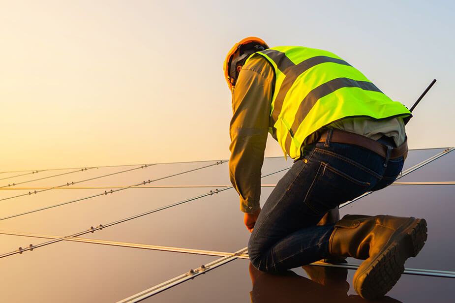 A skilled tradesman working on a solar panel installation at sunset, harnessing the power of renewable energy.