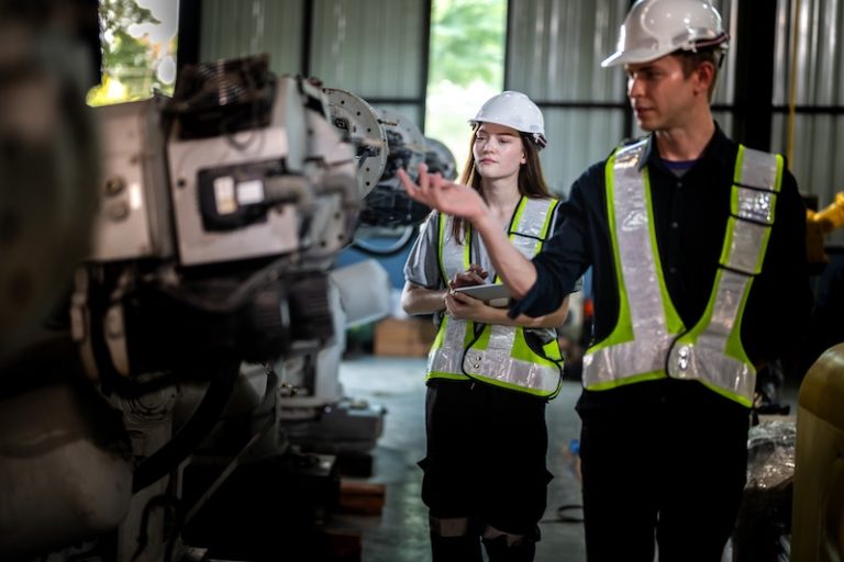 Factory engineers inspect on machine. Confident team mature businessman with laptop standing by robotic arm in industry businessman inspect at height technology for produce the electronic part device.